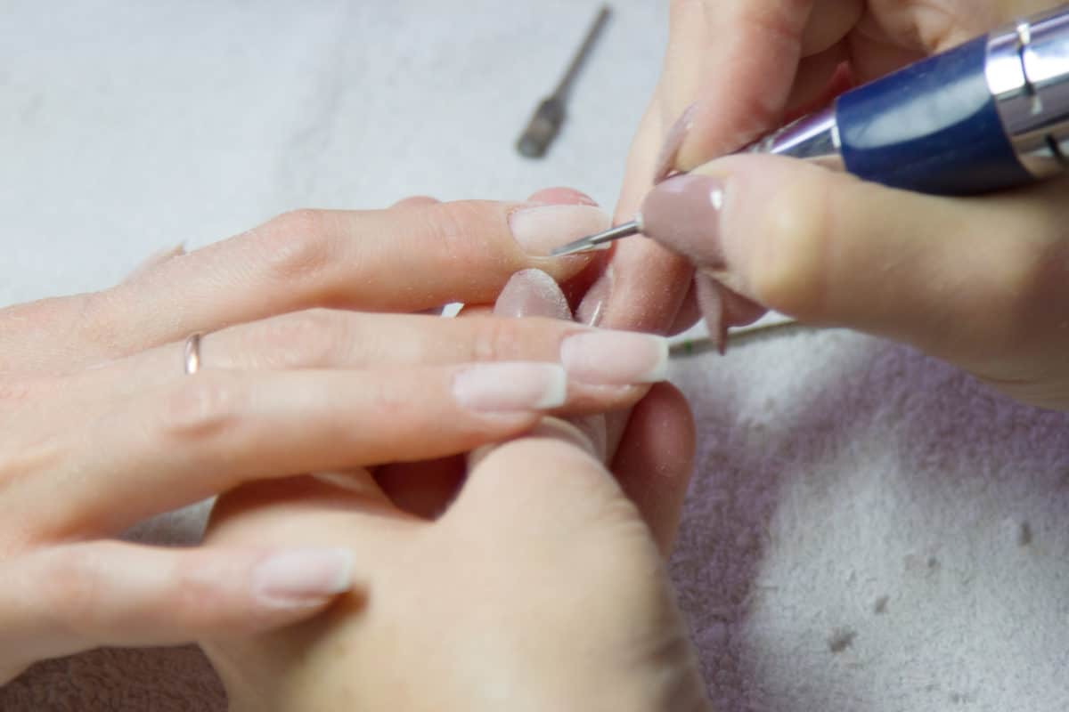 Maniküre mit elektrischem Nagelfräser im Nagelstudio